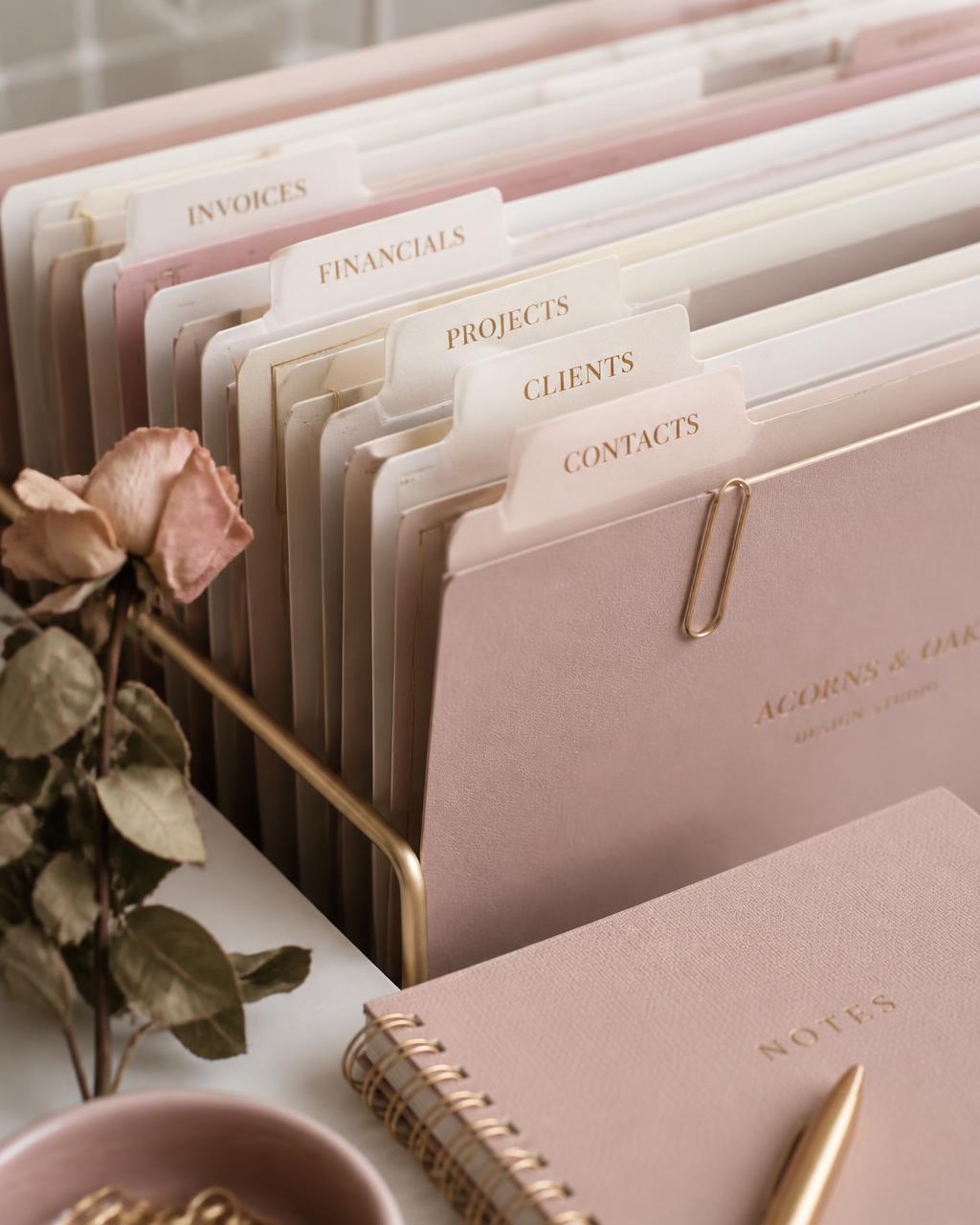 Neatly labeled client folders in blush and cream with gold clips